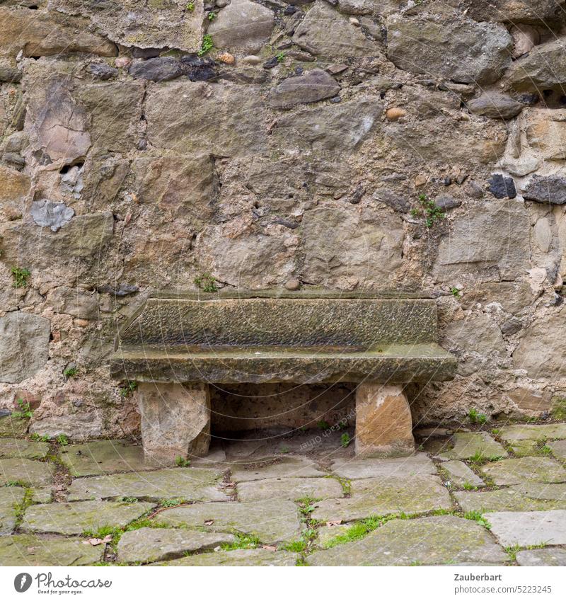 Steinerne Bank vor Steinmauer auf Steinfußboden Steinbank sitzen ruhen hart historisch alt gemütlich ungemütlich Pause ausruhen anlehnen