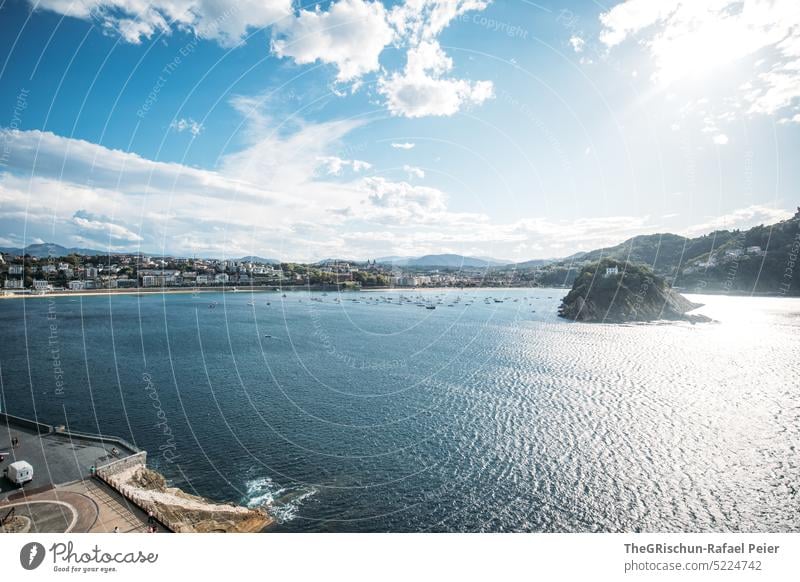 Strand mit Stadt und Hügel im Hintergrund Sonne Häuser Meer Wasser Sommer blau Natur Bucht donostia san sebastian Spanien San Sebastián Baskenland Landschaft