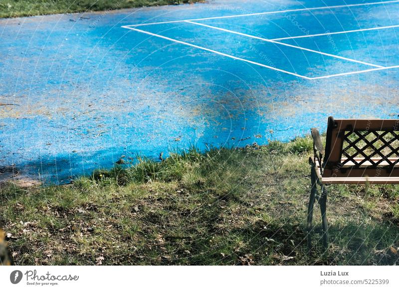 Angeschnittener Tennisplatz, blauweiß mit Bank angeschnitten grün Sport Spielen Linie Spielfeld Menschenleer Sportstätten Licht von draußen verlassen urban