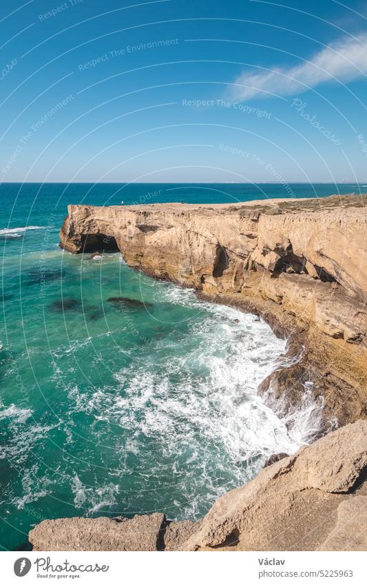 Atemberaubende Klippen mit krachenden Wellen in der Nachmittagssonne an der Atlantikküste bei Vila Nova de Milfontes, Odemira, Portugal. Auf den Spuren der Rota Vicentina. Wanderweg der Fischer. Klarer blauer Himmel