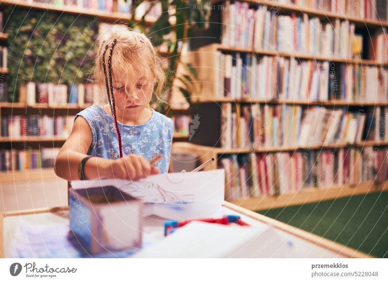 Schulmädchen macht Hausaufgaben. Grundschüler lernen, zeichnen Bilder in der Schulbibliothek. Grundschülerin im Schulclub. Zurück zur Schule Rücken Schüler