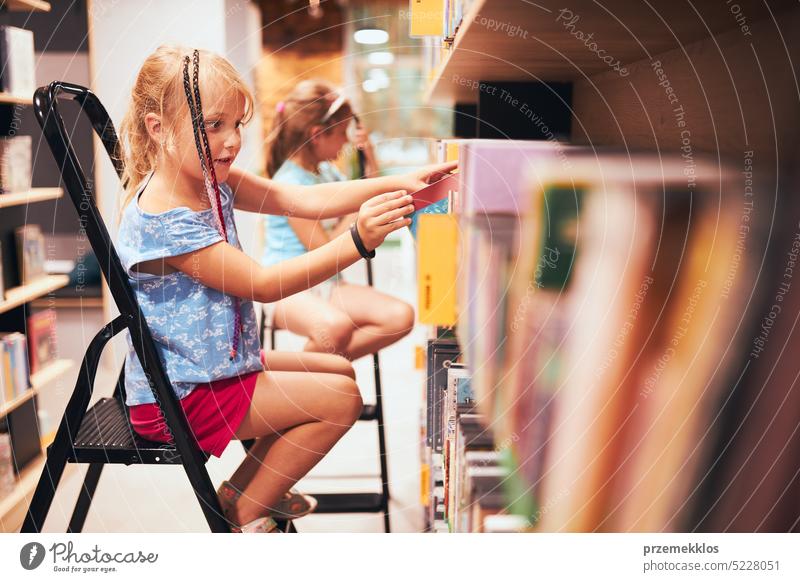 Schülerinnen suchen in der Schulbibliothek nach Büchern. Schüler wählen Bücher aus. Grundschulbildung. Erledigung der Hausaufgaben. Zurück zur Schule Rücken