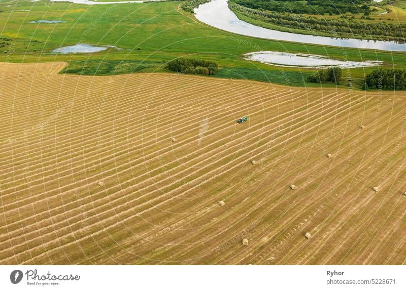 Luftaufnahme Traktor sammelt trockenes Gras in Strohballen im Weizenfeld. Spezielle landwirtschaftliche Ausrüstung. Heuballen, Heu machen.