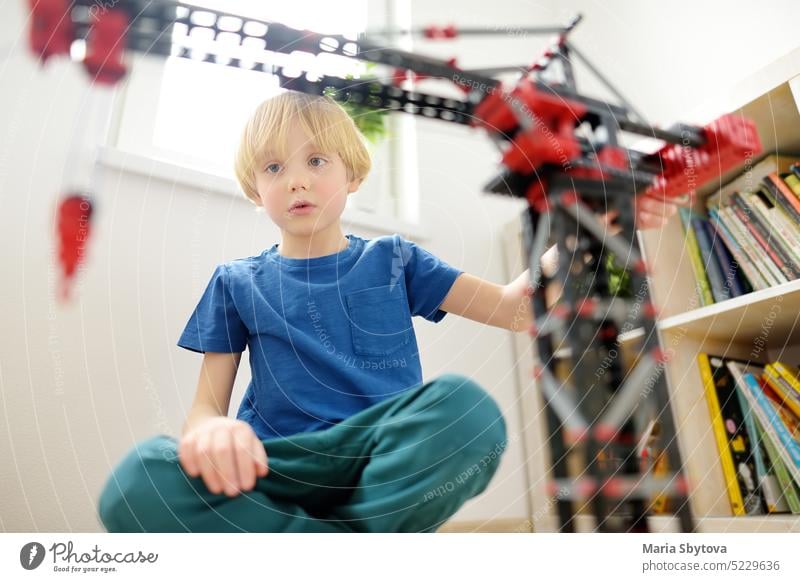 Preschooler Junge spielt mit großen Bau Gebäude Kran Spielzeug zu Hause. Kinder Freizeitbeschäftigung. Unterhaltung für Kinder in Innenräumen. Offline-Spiele.