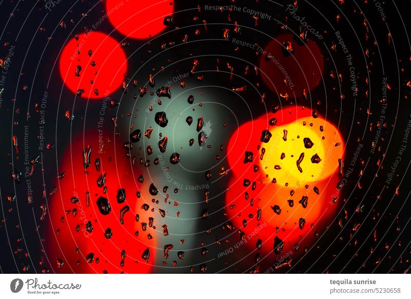 Regentropfen auf Scheibe in der Nacht vor roten Lichtern Tropfen nass Glas Glasscheibe Fenster Fensterscheibe Farbe Farbfoto orange bunt Ampel Autolicht