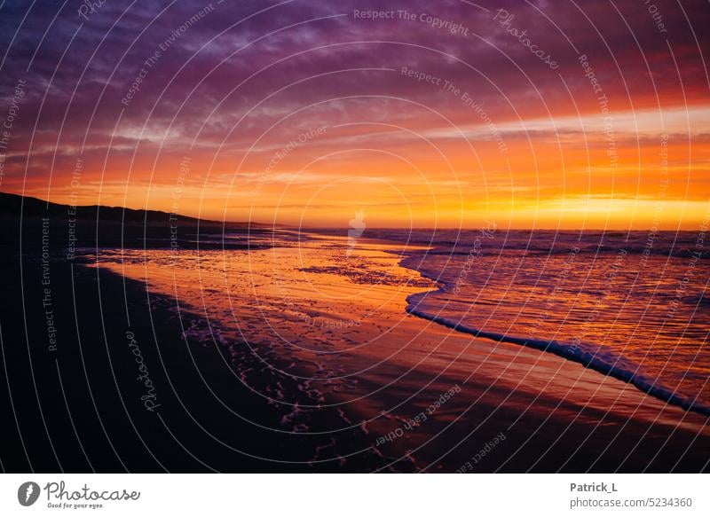 Nordseestrand im Sonnenuntergang mit auslaufender Welle Wasser Wellen Weite Farben Strand Meer Weitblick grenzenlos Horizont Lichtspiel Wolken Himmel Küste