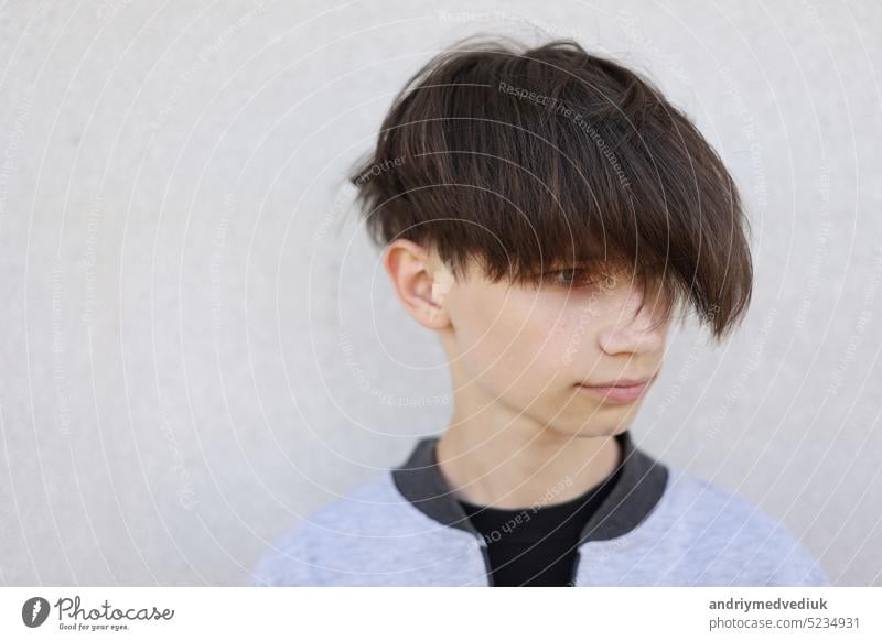 Schöner junger Mann mit stilvollem Haarschnitt. Porträt von Teenager-Junge mit Jugendfrisur steht auf grauem Hintergrund. Gesicht gutaussehend Lifestyle Frisur