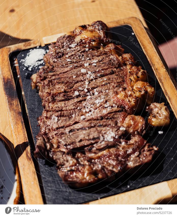 Gegrilltes Ribeye-Steak auf Holzbrett. Gegrilltes Fleisch mit Sauce. Hintergrund Barbecue grillen Rindfleisch Beefsteak schwarz Holzplatte gekocht