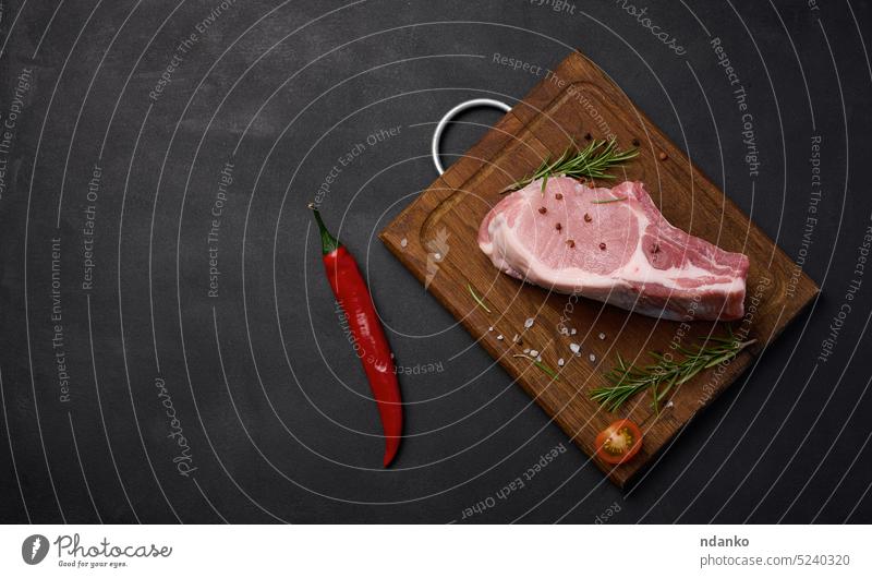 Rohes Schweinefilet mit Knochen und Gewürzen auf einem Schneidebrett aus Holz. Portion für Mittag- und Abendessen, Ansicht von oben. Platz zum Kopieren