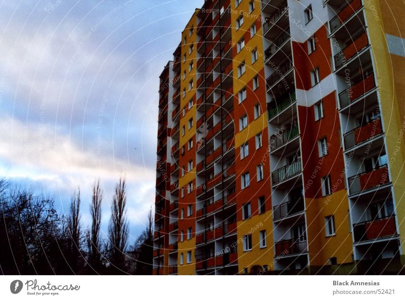 Farbige Tristesse Gebäude Plattenbau Balkon gelb rot Wolken Baum Macht orange Himmel bedecken groß Perspektive