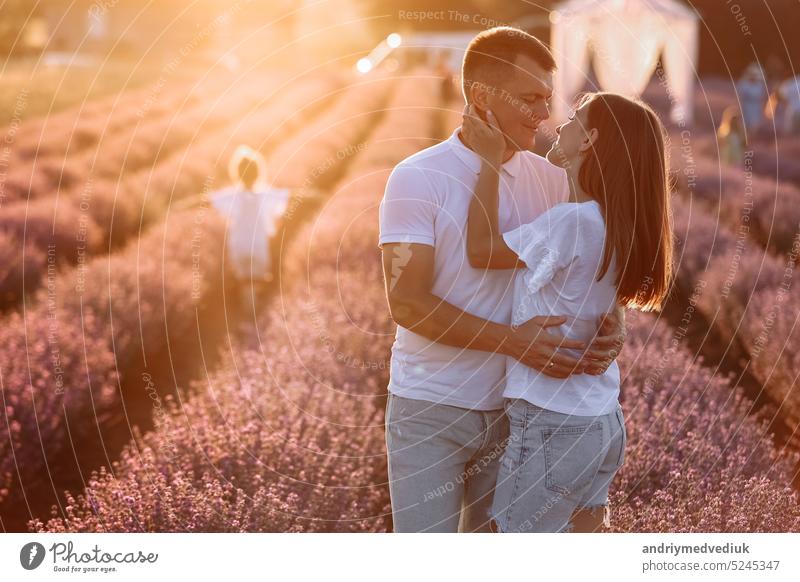 glückliche familie tag. junger vater, mutter und kind tochter haben spaß zusammen im lavendelfeld auf sonnenuntergang. glückliches paar mit kind genießen sommerurlaub urlaub. familie schauen