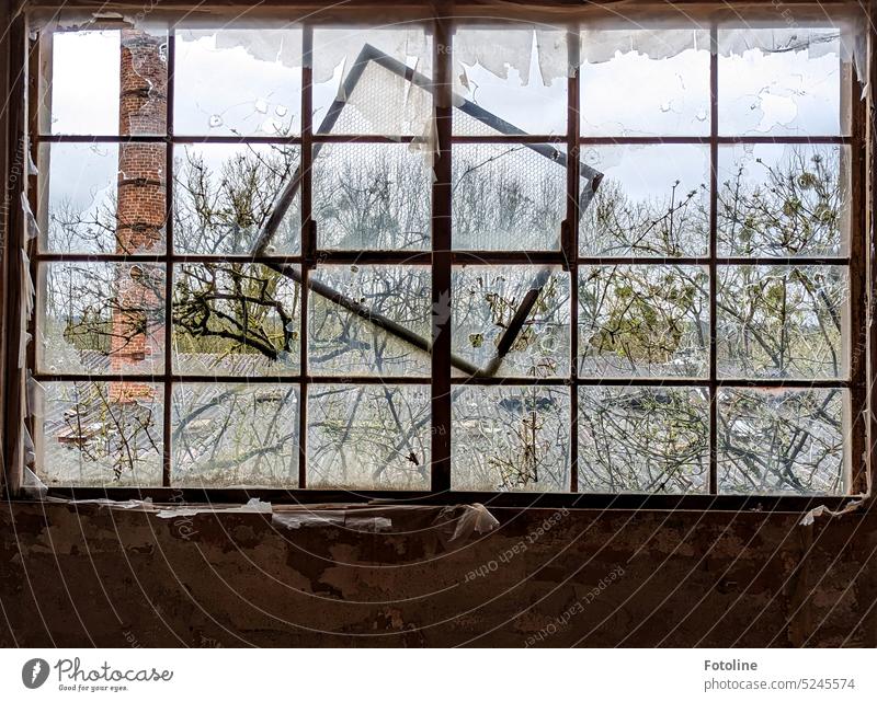 Ein wenig aus der Fassung geraten. Locker hängt ein Fensterrahmen vor einem anderen Fenster mit zerschlagenen Scheiben. lost places alt Verfall Vergänglichkeit