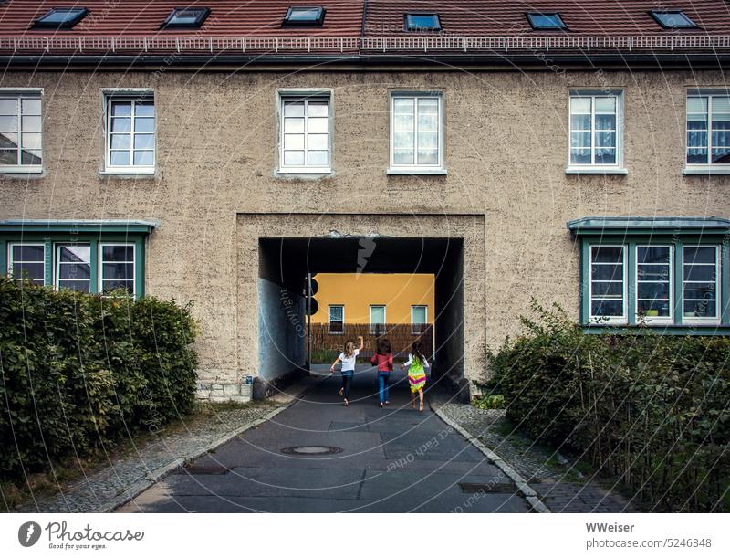 Drei Mädchen spielen zusammen in einer historischen Wohnhaussiedlung Siedlung Wohnsiedlung Stadt Kindheit Kinder Abenteuer rennen fröhlich lebhaft