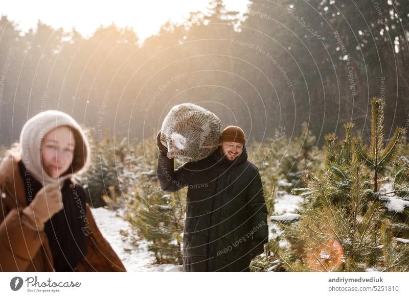 Liebe romantische junge Paar Frau, Mann in verschneiten Winterwald mit Tanne. Wandern, Spaß haben, lachen in stilvoller warmer Kleidung. Schnee Lovestory. Romantisches Date, Wochenende. Frohe Weihnachten und Neujahr