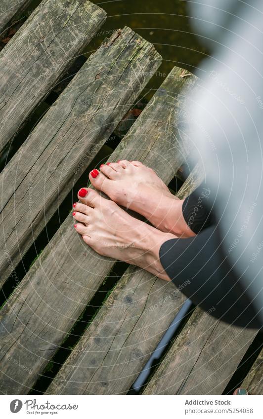 Beine der Ernte Frau auf Pier Fuß See Pediküre nageln Erholung tagsüber Barfuß Dame hölzern Natur Wasser ruhig ruhen Harmonie Park Leggings rot polnisch Urlaub