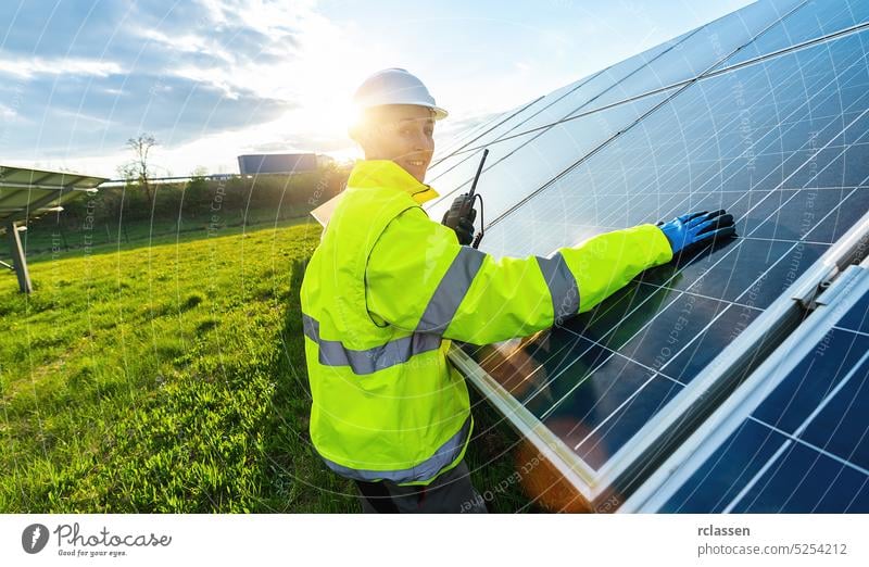 Weiblicher Ingenieur, der in einem Walkie Talkie spricht, um Sonnenkollektoren zu kontrollieren oder zu überwachen, und lächelt glücklich. Nachhaltige Energie und Solarenergie Feld Konzept Bild