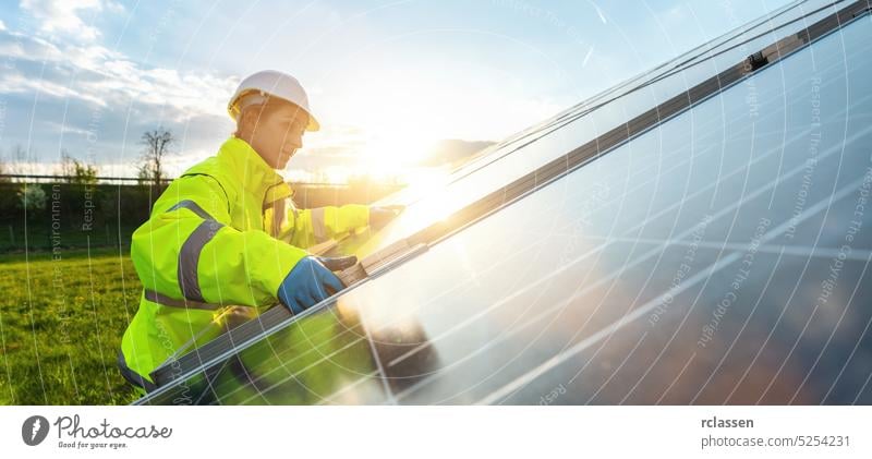 Eine Ingenieurin montiert ein Solarpanel in einem Solarfeld bei Sonnenuntergang. Nachhaltige Energie und Solarenergie Feld Konzept Bild Installateur