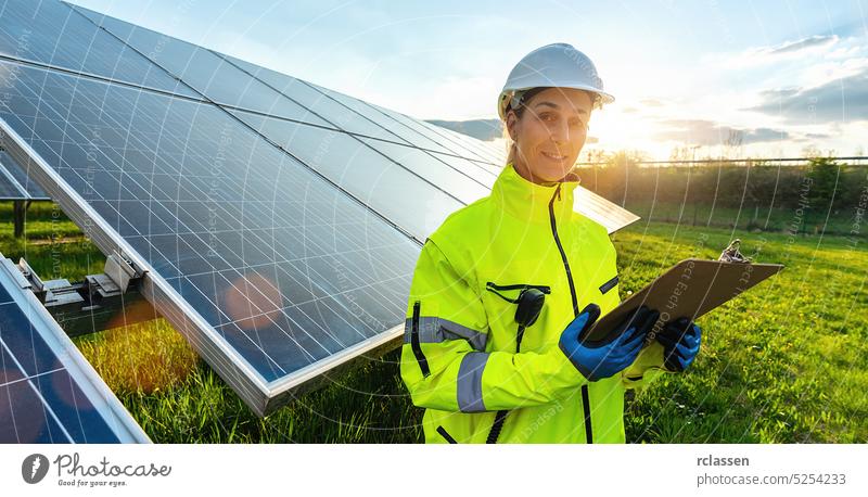 Weiblicher Ingenieur schaut weg, während er Sonnenkollektoren überwacht und lächelt glücklich. Nachhaltige Energie und Solarenergie Feld Konzept Bild Panel