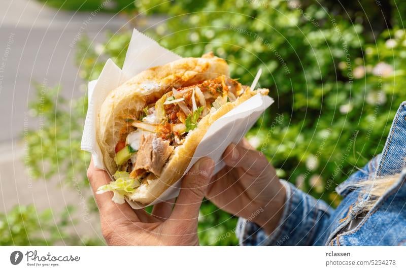 Frau hält einen Döner Kebab (Sandwich), den in Deutschland berühmten Kebab-Schnellimbiss in Fladenbrot. Hand Restaurant Belegtes Brot Snack essen frisch