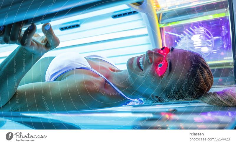 Attraktive junge Frau bräunt sich im Solarium mit Brille Bräune Salon Menschen Licht Spa Behaarung Sonne Schönheit Gesicht Medizin Lifestyle Kosmetik Haut sexy