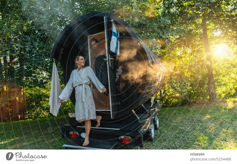 Entspannte Freundinnen kommen aus einer Holzfass-Sauna im Sommer in Norwegen. Sie sind entspannt, lachen und genießen den Urlaub beim Entspannen in der finnischen Saunakabine.