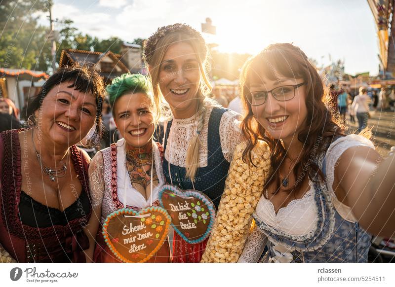 Freundinnen in traditioneller bayerischer Kleidung Dirndl oder Tracht mit Schenk mir dein Herz, Du bist die beste auf Lebkuchenherz auf dem Oktoberfest geschrieben