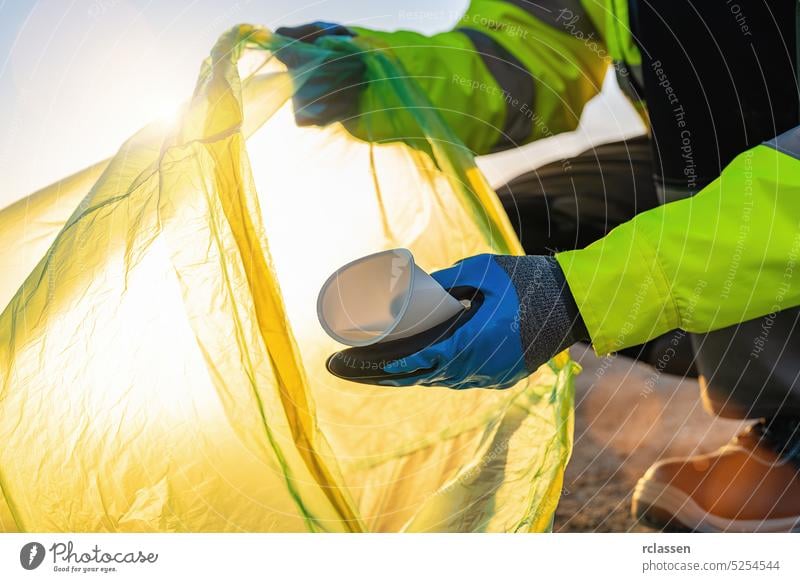 Freiwilliger sammelt Plastikmüll im Park bei Sonnenuntergang. Konzept für eine saubere Umwelt Müll Aktivist Tasche Behälter Flasche Sauberkeit Erhaltung