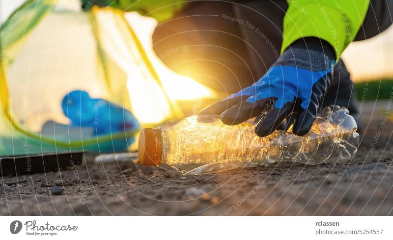 Freiwillige Frau sammelt Plastikmüll im Park bei Sonnenuntergang. Konzept zur Reinigung der Umwelt Müll Aktivist Tasche Behälter Flasche Sauberkeit Erhaltung