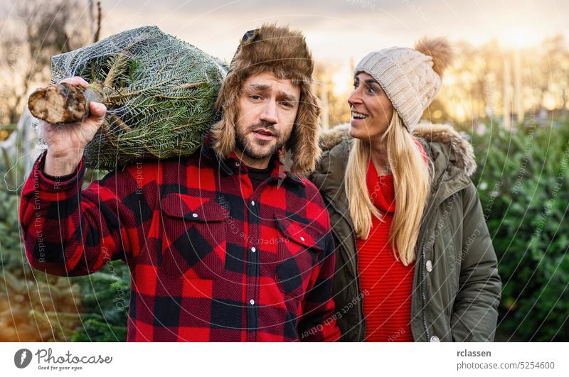 Mann und Frau, die einen Weihnachtsbaum gekauft haben und ihn nach Hause tragen Kiefer Weihnachten Menschen Baum Liebe Winter Mädchen Sale Paar Lächeln niedlich