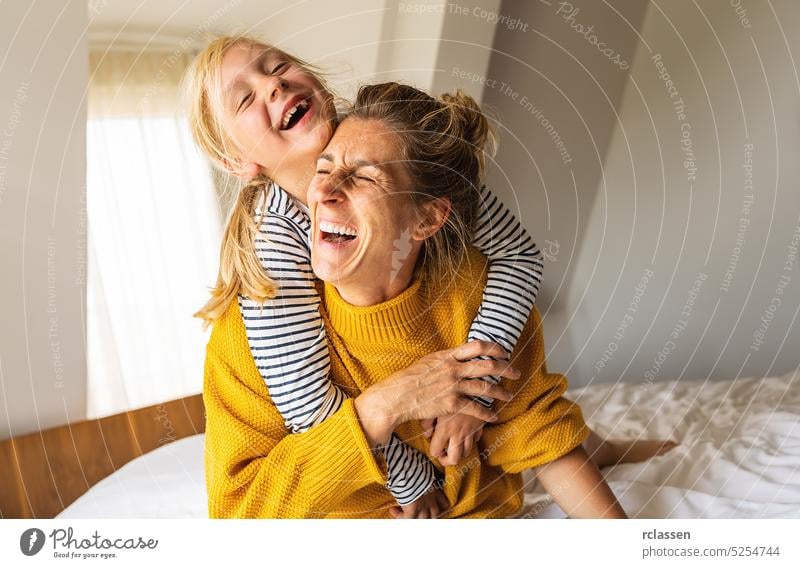 Mädchen und ihre Mutter spielen im Schlafzimmer. Gute Zeit zu Hause. Familie spielt auf dem Bett im Schlafzimmer. Huckepackverkehr Mama heimwärts Tochter