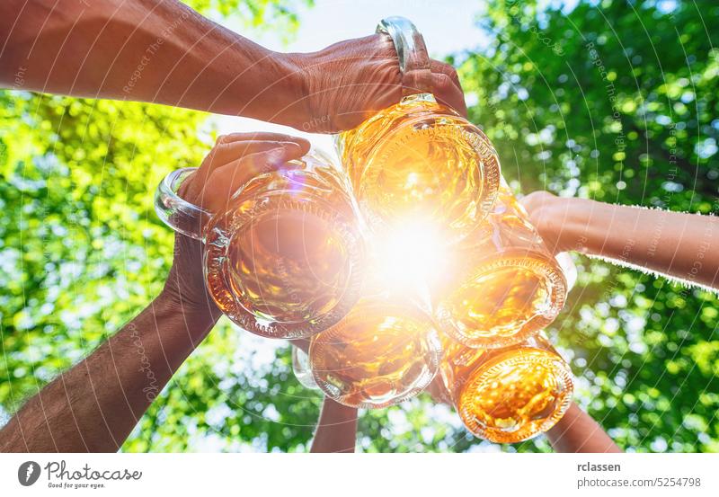 Freunde stoßen an und trinken Bier im Biergarten. Freundschaft Lebensstil und Partei auf Oktoberfest, Volks-oder Bierfest, mit hellem Sonnenlicht Wasserhahn