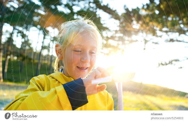 junges Kind hält und spielen mit Windrad-Modell bei Sonnenuntergang am Strand Wald. Neue Energieproduktion mit sauberen und erneuerbaren Energien Konzept Bild