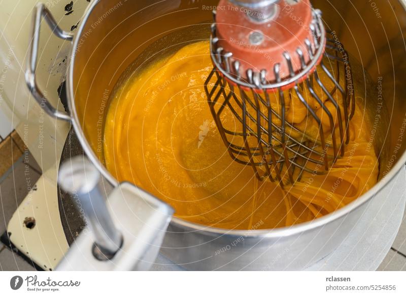 Mischen von Backzutaten mit Eigelb und Zucker in einer großen Küchenmaschine für Kuchen oder Pfannkuchen. Konzept eines Bäckereiladens. Geschwindigkeit