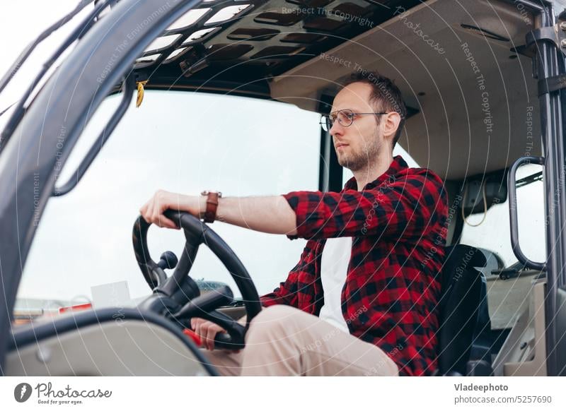 Junger Fahrer eines Traktors oder Mähdreschers auf dem Lande, der in der Kabine sitzt. Ackerbau und Ernte landwirtschaftlich Transport Fahrzeug arbeiten Porträt