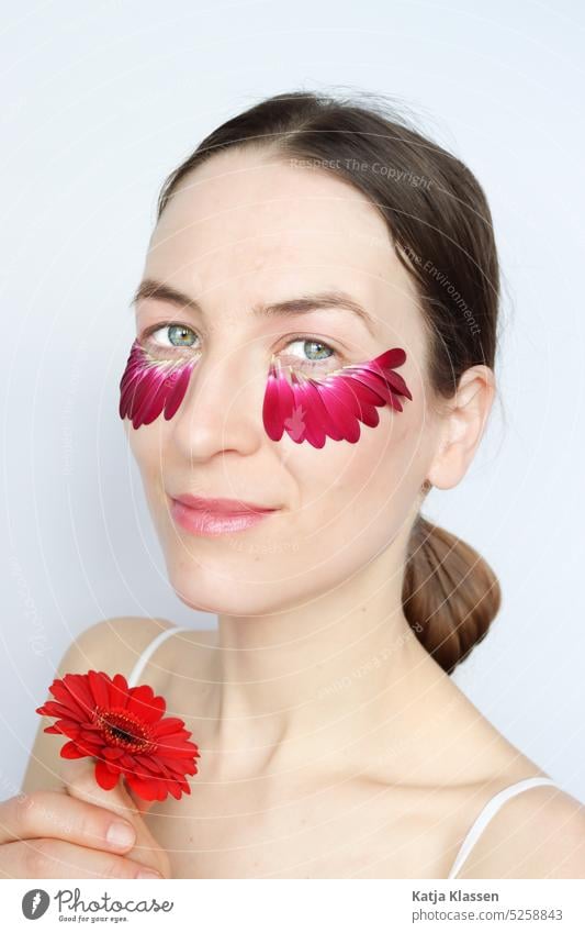 Portrait einer Frau mit roter Blume in den Händen und Blütenblätter unter den Augen Junge Frau Rote Blume in den Händen Blumenblätter unten den Augen hübsch