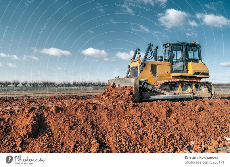 Planierraupe bei der Arbeit auf einer Baustelle oder in einem Steinbruch. Bergbaumaschinen bewegen Ton, glätten Schotteroberfläche für neue Straße. Erdbewegung, Ausgrabungen, Graben auf Böden.