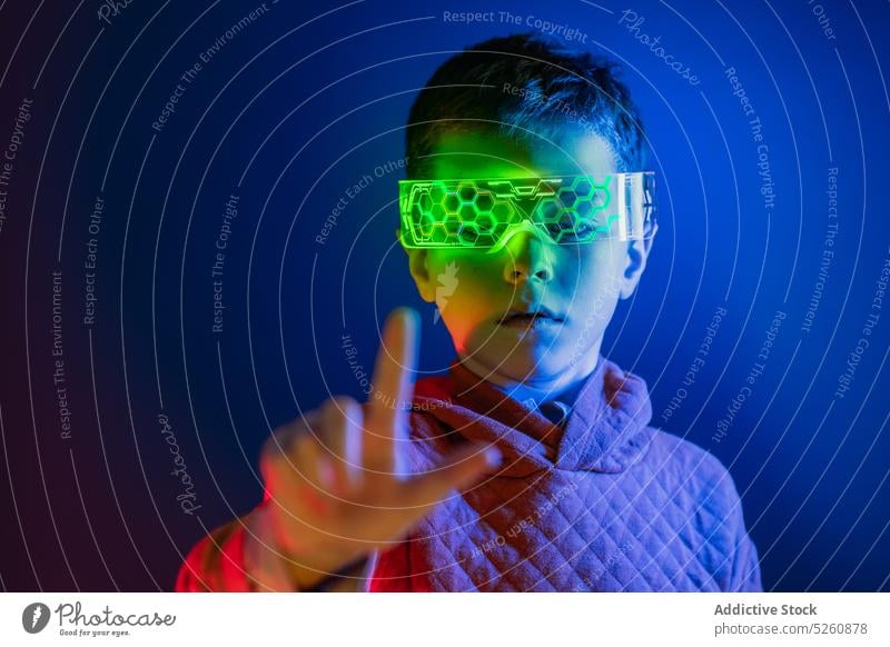 Junge mit intelligenter Brille berührt unsichtbaren Bildschirm Kind Touchscreen klug VR Schutzbrille futuristisch Innovation Cyberspace blättern durchziehen.