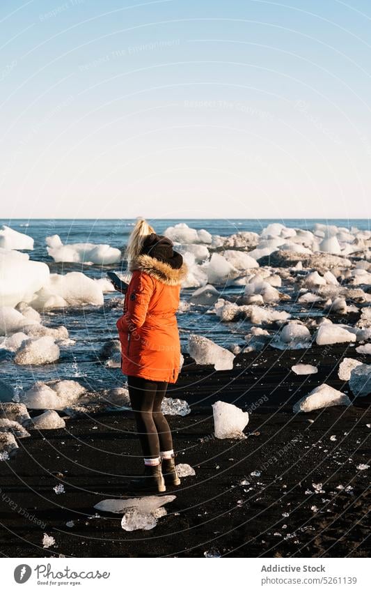 Schwarzer Sandstrand mit Gletschereisblöcken Frau Eis Klotz Reisender kalt Winter Strand Ufer Natur Island Europa MEER Meeresufer Küste gefroren Abenteuer