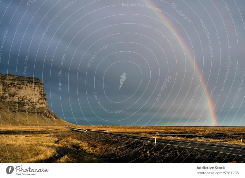 Landstraße in der Nähe felsigen Klippe unter bewölktem Himmel mit Regenbogen Straße Wiese Landschaft Natur vulkanisch Berge u. Gebirge Tal atemberaubend wolkig