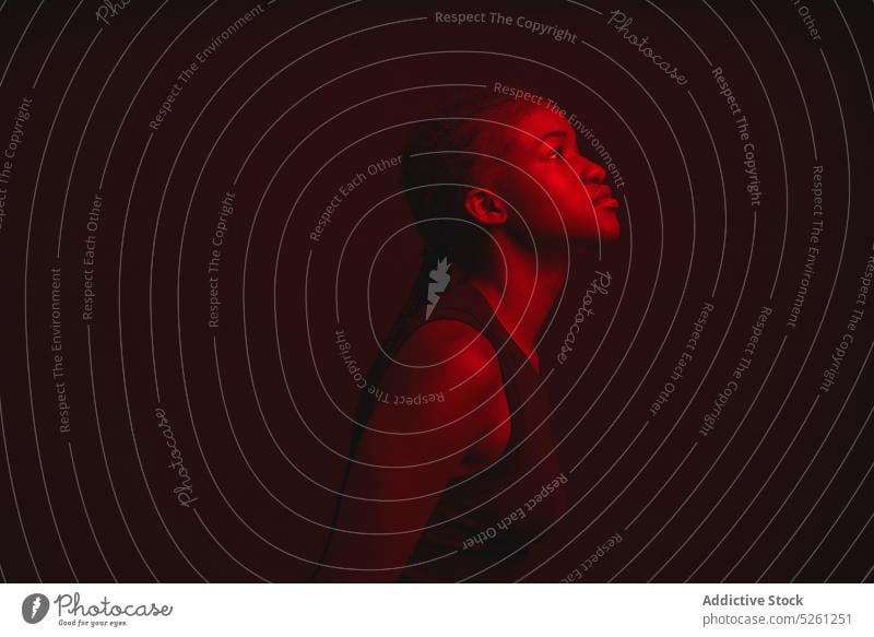 Verträumte ethnische Frau in der Dunkelheit besinnlich nachdenklich verträumt rot leuchten dunkel Stil Geflecht Raum Windstille ernst Licht jung ruhig