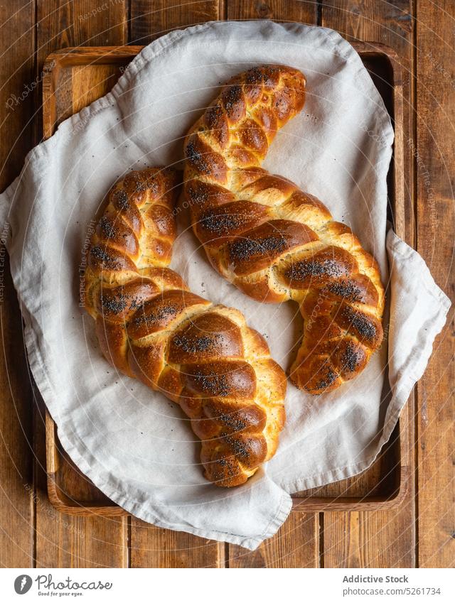 Leckere süße Brotzöpfe auf Handtuch Brotlaib Tablett dienen Mohn rustikal golden Mahlzeit Serviette geschmackvoll Geflecht challah Bäckerei frisch lecker