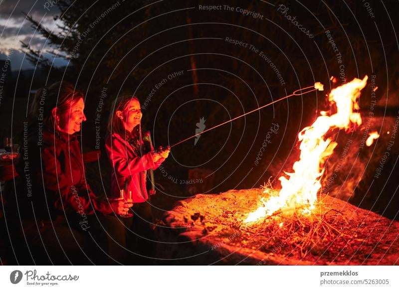 Familie sitzt am Lagerfeuer in den Sommerferien. Mutter und Tochter verbringen Zeit am Sommerwochenende. Urlaubsreise in der Nähe der Natur Camping Freunde