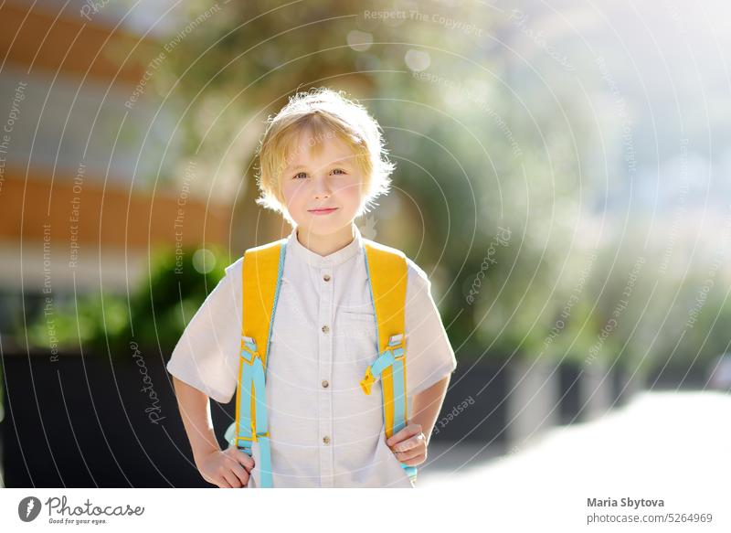 Kleiner Schuljunge geht nach den Ferien freudig zur Schule. Kind auf dem Hof eines Schulhauses. Gute Bildung für Kinder. Kinder zurück in der Schule Porträt