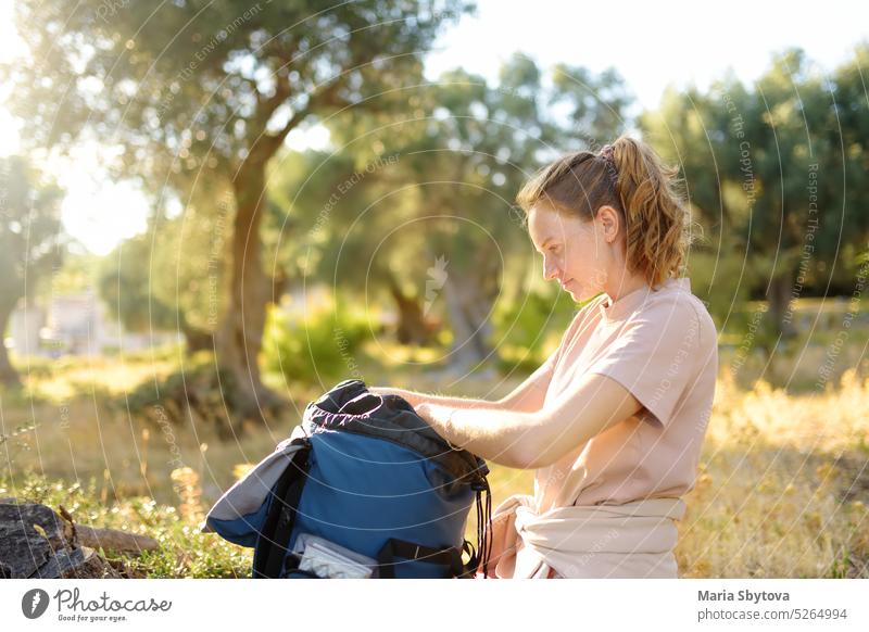 Junge Frau packt ihren Rucksack beim Wandern in der sommerlichen Natur. Konzepte von Abenteuer, extremes Überleben, Orientierungslauf. Ausrüstungen für die Wanderung.