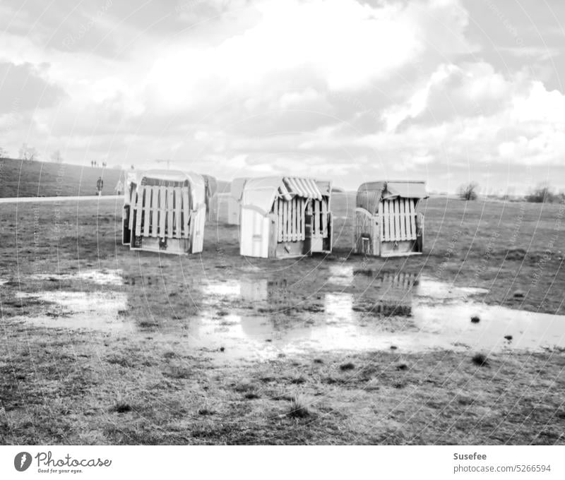 Geschlossene Strandkörbe bei schlechtem Wetter am Nordseestrand in schwarz-weiß Strandkorb Küste Ferien & Urlaub & Reisen Meer Schwarzweißfoto Einsam traurig