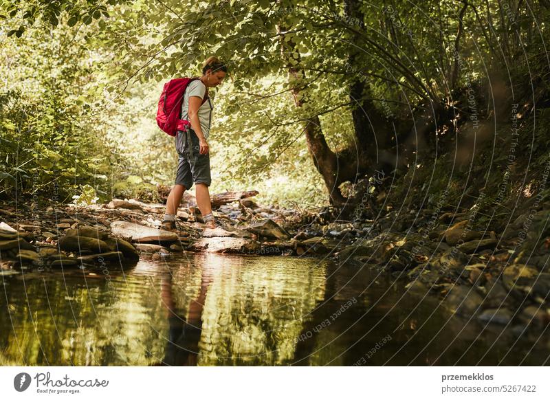 Reisen mit Rucksack Konzeptbild. Backpacker weiblich in Trekking-Stiefel überqueren Berg Fluss. Sommerurlaub Reise Abenteuer reisen Ausflug Urlaub