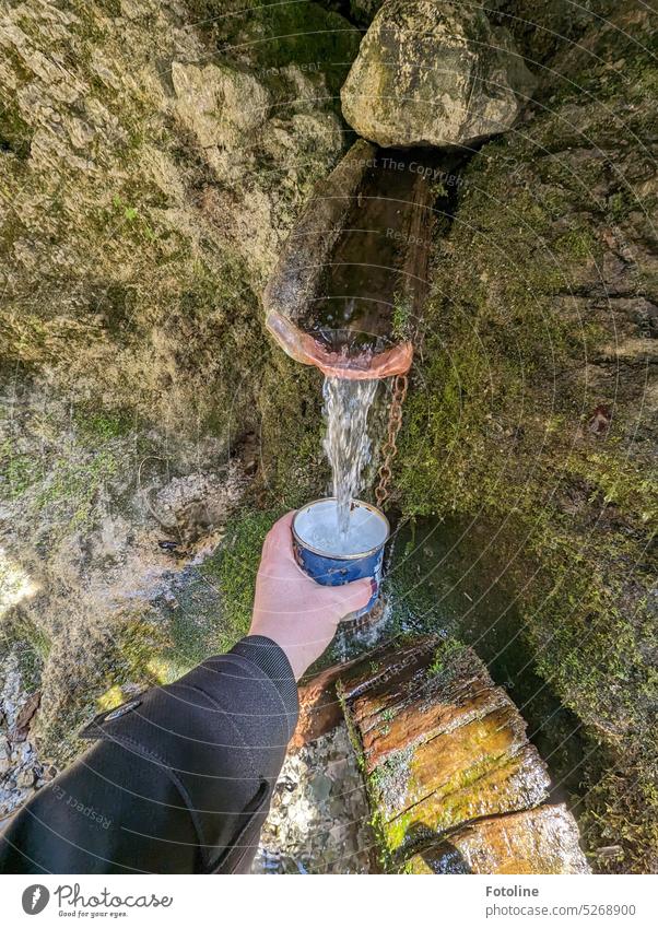 In der Kundler Klamm in Österreich muss keiner verdursten. Ein kleiner metallener blauer Becher ist mit einer Kette am Stein befestigt. Aus dem Stein sprudelt eine kalte, klare Quelle. Meine Hand hält den Becher und lässt ihn voll laufen.