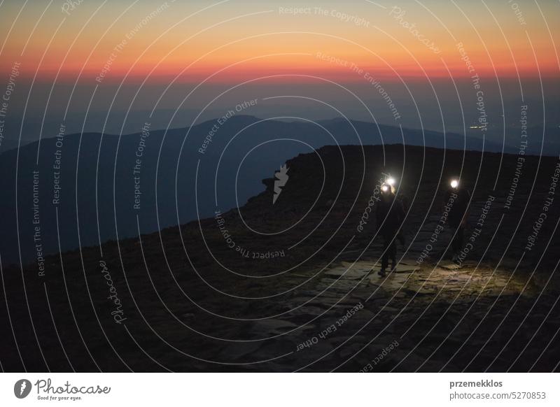 Menschen wandern bei Nacht. Berge bei Sonnenaufgang. Mann steht auf Gipfel. Natürliche Berglandschaft mit beleuchteten nebligen Gipfeln, nebligen Hängen und Tälern