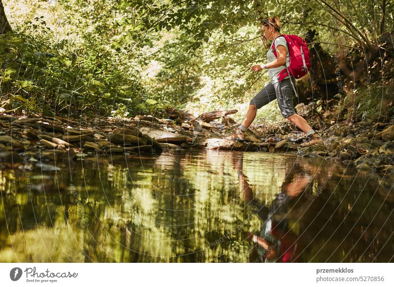 Reisen mit Rucksack Konzeptbild. Backpacker weiblich in Trekking-Stiefel überqueren Berg Fluss. Sommerurlaub Reise Abenteuer reisen Ausflug Urlaub