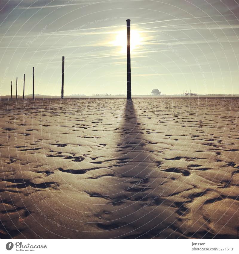 Ein Pfahl am Strand von St. Peter-Ording wirft einen langen Schatten im Sonnenuntergang sankt peter-ording Sommer schön Sonnenlicht Gegenlicht